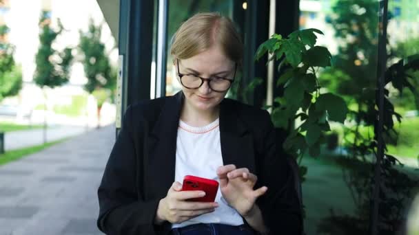 在户外用手机微笑的女商人 小企业主一边看着自己的手机 一边微笑着与同事交流 高质量的 — 图库视频影像