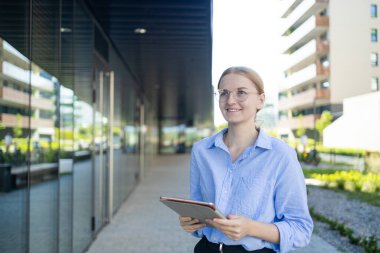 Young elegant professional leader Caucasian woman, female executive retail manager supervisor, small business owner wearing suit holding digital tablet standing outdoor looking at camera, portrait.