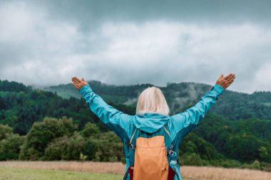 Dağın tepesindeki yaşlı kadının manzarası güzel manzaranın keyfini çıkarıyor, kolları açık duruyor, kanyon ulusal parkında yürüyüş yapıyor. Yüksek kalite fotoğraf