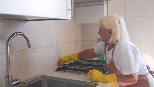 50多岁的家庭主妇戴着橡胶手套 在家里擦拭厨房表面 保持房子整洁 快乐的专业清洁女工清扫室内灰尘 优质Fullhd影片 — 图库视频影像
