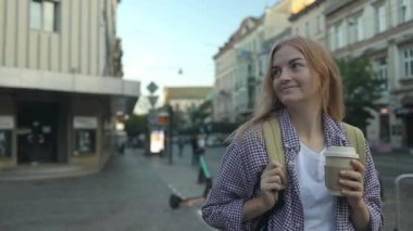 Eski şehirde sokakta elinde kahve fincanı olan genç bir kadının hayat tarzı portresi. Krakow, Polonya. Yüksek kaliteli FullHD görüntüler