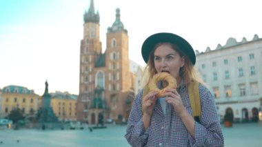Genç bayan turist elinde simit, obwarzanek, pretzel. Krakow 'daki Pazar Meydanı' nda geleneksel Polonya atıştırması. 