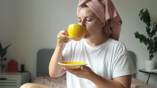 美丽而轻松的女人 在床上思量着 喝咖啡 早上带着微笑和安慰放松 卧室里的女人带着茶杯醒来 快乐的回忆和健康的身体 — 图库视频影像