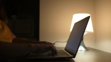 Geceleri masa başında oturan ve dizüstü bilgisayarına bir şeyler yazan tanınmayan bir kadın. Yüksek kaliteli FullHD görüntüler