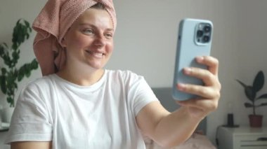 Video görüşmesi, telefon ve yatak odasında konuşan ve selamlaşmak için öpücük yollayan genç bir kadın. Yüksek kaliteli FullHD görüntüler