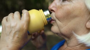 Ormanda dinlenen termoslu yaşlı kadın turistin resmini çek. Dağda yürüyüş sırasında rahatlama. Yüksek kaliteli FullHD görüntüler