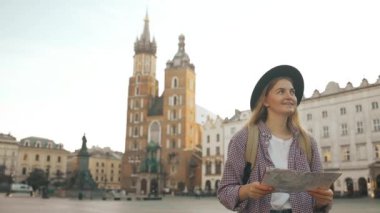 Krakow 'daki eski Pazar Meydanı' nda elinde turist haritası olan gezgin bir kadının gerçek görüntüsü. Seyahat ve aktif yaşam tarzı konsepti. Yüksek kaliteli FullHD görüntüler