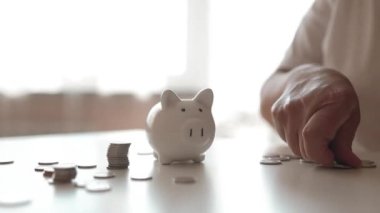 50 'li yaşlardaki yaşlı bir kadın para biriktirmek ve finansal konsept için domuzcuğa para yatırıyor. Yüksek kaliteli FullHD görüntüler