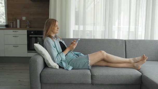 Genç Beyaz Sarışın Bir Kadın Kanepeye Uzanıp Sohbet Ediyor Akıllı — Stok video