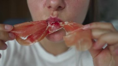 Evde geleneksel İspanyol usulü kurutulmuş jambon yiyen genç bir kadının portresi.