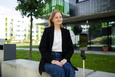 Dijital kameralı kadın video kaydedici. Gülümseyen kadın yaz şehrinde selfie videosu çekiyor. Gezgin blogu için video çekiyor. Vlogger sosyal medyayı çekmek için fotoğraf makinesi kullanıyor. Yüksek kalite fotoğraf