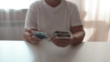 Son 50 'lerin mutlu kadını masa, ofis ve not defterine oturur ve elinde dolarlarla para sayar. Finansal muhasebe. Gelir, kâr, zenginlik. Yüksek kaliteli FullHD görüntüler