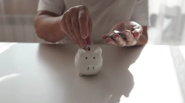 50 'li yaşlardaki yaşlı bir kadın para biriktirmek ve finansal konsept için domuzcuğa para yatırıyor. Yüksek kaliteli FullHD görüntüler