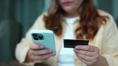 İnternetten alışveriş. Akıllı telefon tutan bir kadın ve geçmişi bulanık olan bir kredi kartı. Kredi kartı ödemesi, mobil bankacılık..