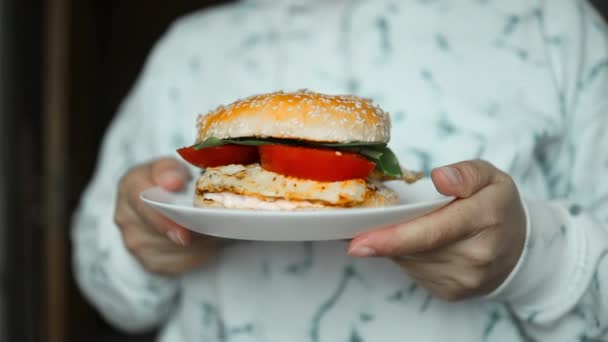 タマネギ トマト チーズ レタス ホワイトプレートのソースで新鮮なおいしい自家製バーガーを保持している女性の手のクローズアップ高品質フルHd映像 — ストック動画
