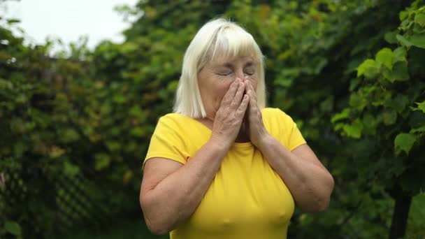 病気の大人の50代の女性は夏に公園に立っているティッシュで鼻を吹きます 高品質のフルHd映像 — ストック動画