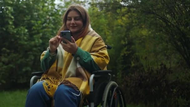 장애가있는 세련된 여성은 전화를 사용하고 뉴스를 자연에서 공원에서 네트워크에 소통합니다 — 비디오