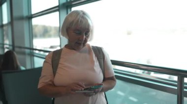 Tatilde havaalanında cep telefonuyla kalkış için bekleyen Kafkasyalı son sınıf öğrencisi kadın. 