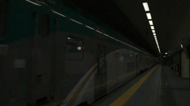 Metro istasyonuna birkaç kişinin geldiği yeşil metro treni. Yeraltı treni platforma varıyor. Avrupa modern toplu taşımacılığı. Milan, İtalya - 13 Ekim 2023. Yüksek kalite