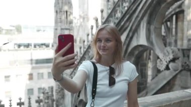 Selfie kızı. Genç bayan turist Milan 'daki ünlü Duomo katedralinin çatısında akıllı telefonuyla selfie çekiyor. Milan 'da iyi tatiller.