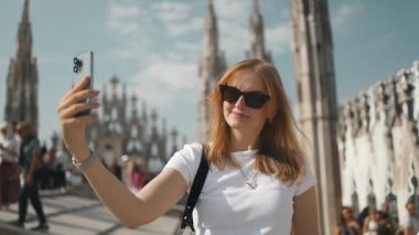 Selfie kızı. Genç bayan turist Milan 'daki ünlü Duomo katedralinin çatısında akıllı telefonuyla selfie çekiyor. Milan 'da iyi tatiller.