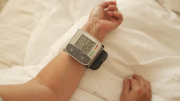 高齢の女性は 自宅で自分でデジタル圧力計で血圧と心拍数をチェックしています 高齢の女性は 健康を世話しています 健康と医療のコンセプト 高品質のフルHd映像 — ストック動画