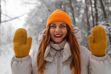 Sıcak giysili ve sarı eldivenli genç bir turist kış kentinde dağ ormanlarında yürüyüş yaparken selfie çekiyor. Kameraya gülümseyen başarılı bir yürüyüşçü 