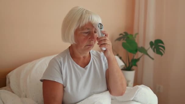 生病的老年妇女患流感躺在沙发上看温度计上的温度 感冒和偏头痛 季节性病毒问题概念 — 图库视频影像