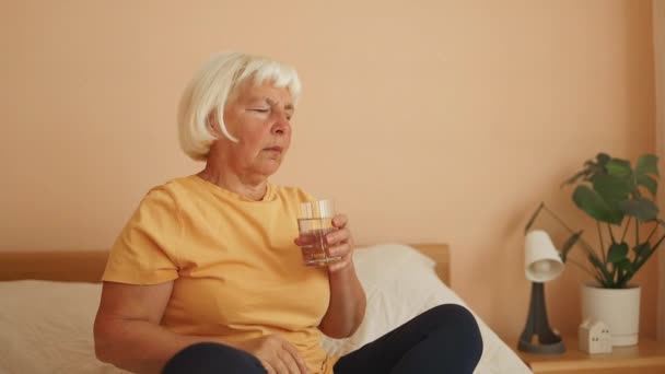 60多岁的老年妇女用圆形药丸和一杯静水止疼药缓解痛感偏头痛 抗抑郁药或抗生素药 急救概念 — 图库视频影像
