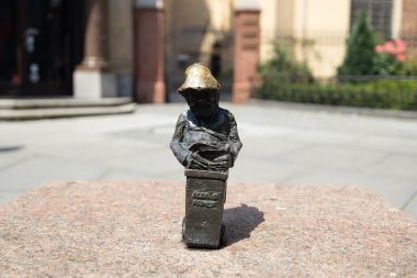 Kadın Wroclaw sokaklarında cücelerin küçük bronz figürlerine dokunuyor. Avrupa. Yüksek kalite fotoğraf