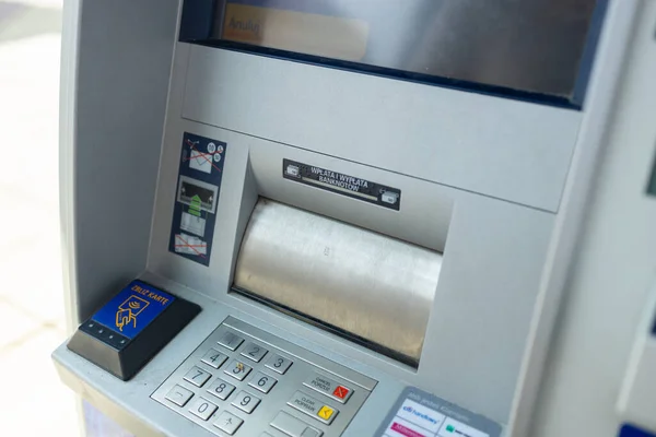 Silver automatic teller machine hanging on a gray concrete wall. High quality photo
