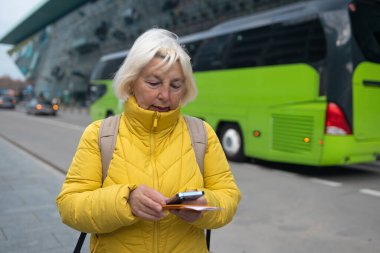 Turist taksi bekliyor. Kıdemli kadın havaalanının dışında durur ve tatilden sonra taksi bekler ya da seyahat eder. Kadın turist eve geldi. Yüksek kalite fotoğraf