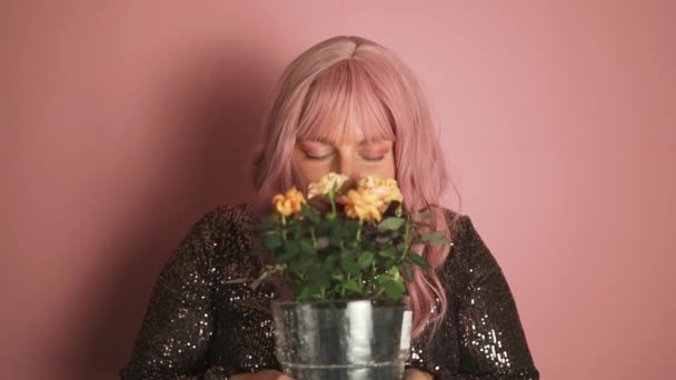 ピンクのスタジオのバックグラウンドでWomans Dayの花の鍋を受け取ることに興奮している豪華な若いピンクの髪の女性 お祝いのコンセプト 高品質のフルHd映像 — ストック動画