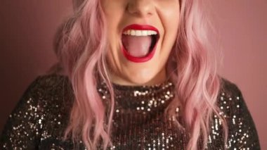 Kırmızı dudaklı, neşeli, güzel bir kız. Pembe arka planda izole bir şekilde kutlanıyor. Yüksek kaliteli FullHD görüntüler