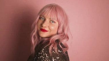 Makyajlı güzel pembe saçlı kadın öpüşür, iyi duygularını gösterir, uzaklarda veda eder, pembe arka planda izole olur. Genç, güzel bir kadın model hava öpücüğü veriyor. Yüksek kalite FullHD