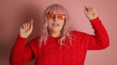 Genç ve çekici pembe saçlı kadın kırmızı kazak giyip yeni yılın tadını çıkarıyor. Yüksek kaliteli FullHD görüntüler