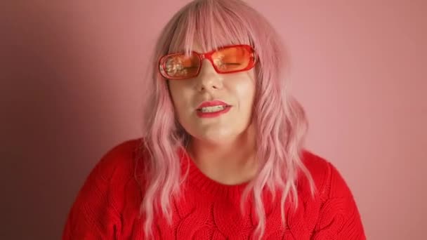 若い魅力的な甘い若いピンクの髪の女性は 新しい年を隔離されたピンク色の背景を楽しむ赤いセーターダンスを着用します 高品質のフルHd映像 — ストック動画