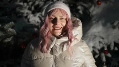 Genç, güzel, pembe saçlı bir kadın kış parkında kollarını sallıyor ve yürüyor.