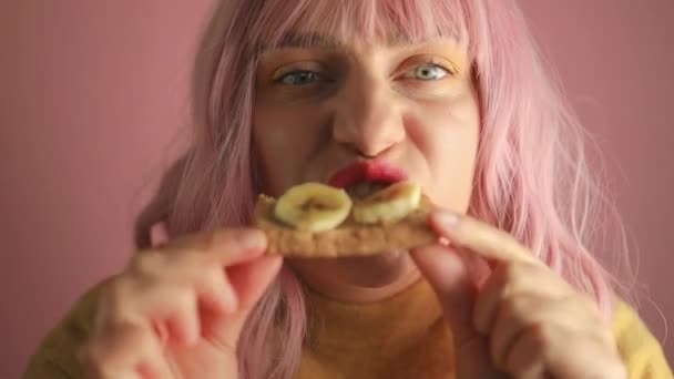 Студійний Портрет Щасливої Розпусної Рожевої Жінки Їсть Смачний Бутерброд Бананом — стокове відео