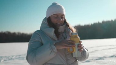 Mutlu kadın soğuk bir kış günü termosla dışarıda çay ya da kahve içer. Çay molası. Kış ve Noel zamanı kavramı. Dinlenme, rahatlama, seyahat, yaşam tarzı konsepti. Yüksek kalite FullHD