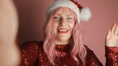 Parlayan kadın gülüşünü kırmızı dudaklarla kapat. Mutlu pembe saçlı Noel Baba şapkalı kadın diş tedavisinden memnun olduğunu gösteriyor. Yüksek kaliteli FullHD görüntüler