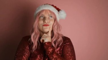 Noel Baba şapkalı genç bir kadının pembe duvar arkasında izole edilmiş olduğunu düşünüyorum. Yüksek kaliteli FullHD görüntüler