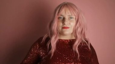 Çekici pembe saçlı beyaz kadın mutlu pozlar veriyor, kameraya bakıp gülümsüyor. Neşeli manken eğleniyor, pembe arka planda kutlama yapıyor.. 