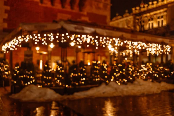 Blurred abstract background of outdoor cafe or restaurant during Christmas holidays of night festival. Outdoor cafe with tables and chairs. Street cafe in the evening in Krakow.