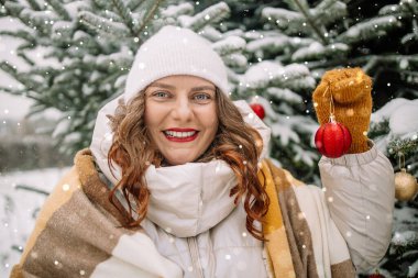 Mutlu Kafkasyalı kadın, kış tatili için karlı arka bahçede hazırlanırken Noel ağacını şenlikli toplarla süslüyor. Yeni yılı kutluyoruz. Yüksek kalite fotoğraf