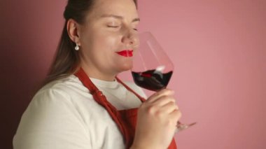 Şatafatlı muhteşem kadın şarap tatma etkinliğinde kırmızı şarap içiyor, içiyor ve popüler bir karışımın kalitesini test etmekten zevk alıyor. Yüksek kaliteli FullHD görüntüler