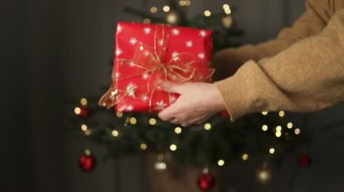Annemin eline bağlı kırmızı hediye kutusu veren tanınmayan bir kızın ellerinin yakın plan görüntüsü. Noel boyunca hediye vermek, mutlu yıllar ve mutlu yıllar. Yüksek kaliteli FullHD görüntüler
