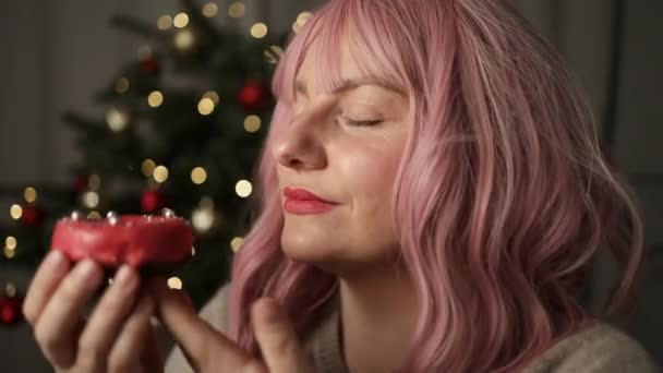 ドーナツのデザートを噛んだ幸せな女性は クリスマスライトの背景の前にカメラを見ます 適切な栄養 健康的なファーストフード 不健康な選択の概念 高品質のフルHd映像 — ストック動画