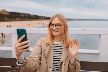 Deniz kenarında cep telefonu tutan ve kullanan güzel beyaz bir kadının portresi. Yüksek kalite fotoğraf