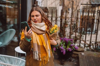 Üzgün 30 'lu yaşlardaki genç bir kadın şehir kafesinin yakınlarında akıllı telefon kullanıyor. Negatif insanların duyguları. Yüksek kalite fotoğraf